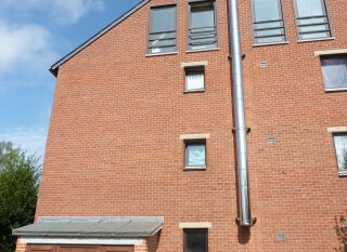 Double-walled stainless steel modular collective chimney, mounted on the outside of the building, for overpressure evacuation of wall-mounted gas-fired condensing boilers